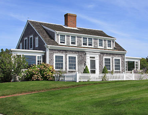 Une maison avec une clôture en piquets blancs et un toit de style Cape Cod